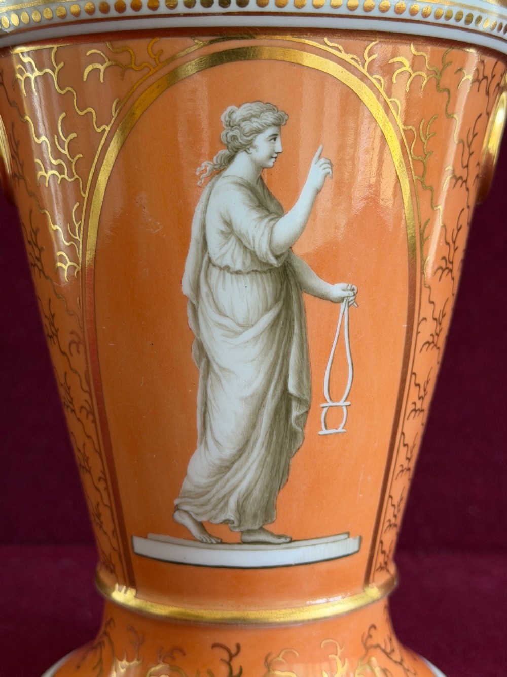 A Regency Flight & Barr Worcester porcelain jardiniere featuring an orange ground, gilt seaweed patterning, and a classical female figure painted in grisaille inside a oval frame. View III