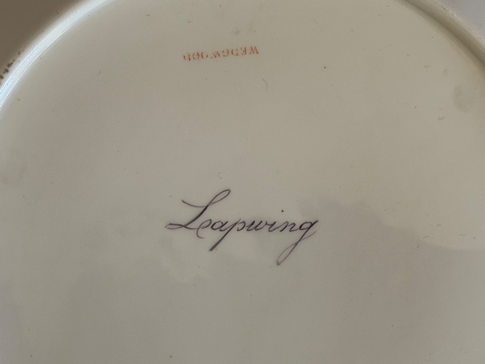 A circular bone china plate featuring a central hand-painted lapwing bird study and feather motifs on the fluted rim with a gilded edge. View III