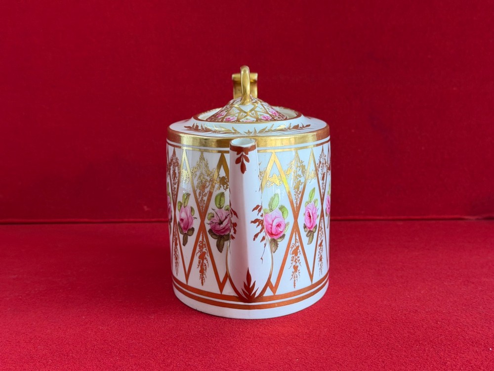 An antique oval white porcelain teapot decorated with hand-painted pink roses inside gilded diamond lozenges and gold rim details. View II