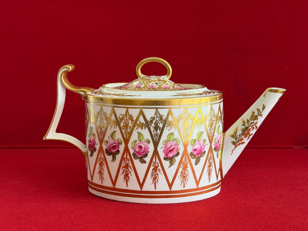 An antique oval white porcelain teapot decorated with hand-painted pink roses inside gilded diamond lozenges and gold rim details. View IV