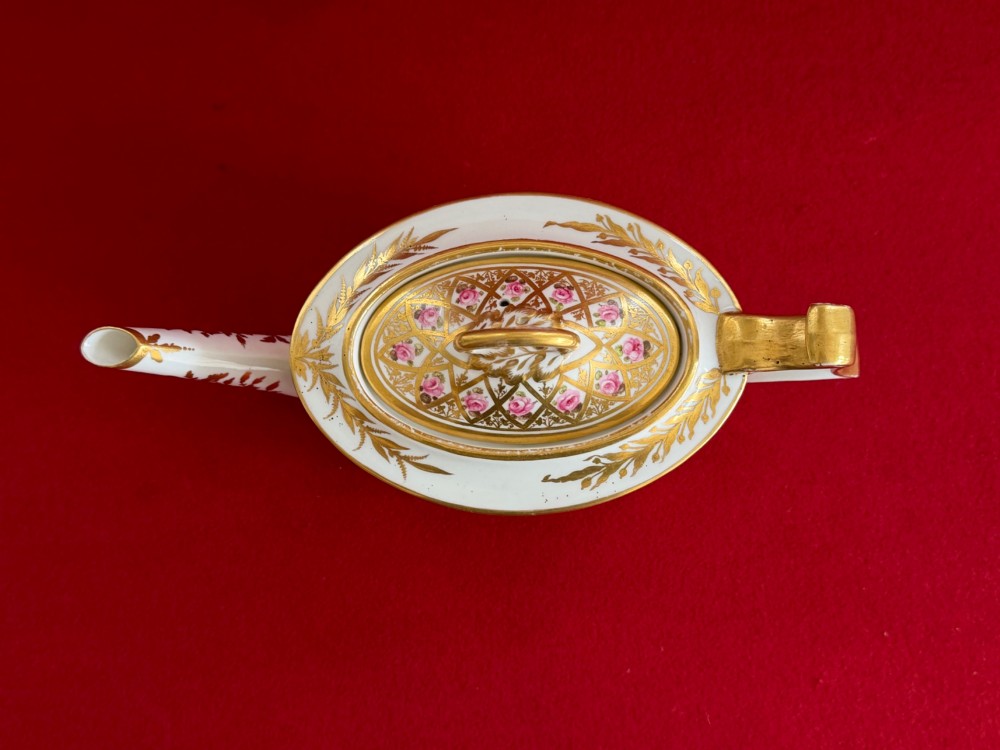 An antique oval white porcelain teapot decorated with hand-painted pink roses inside gilded diamond lozenges and gold rim details. View V