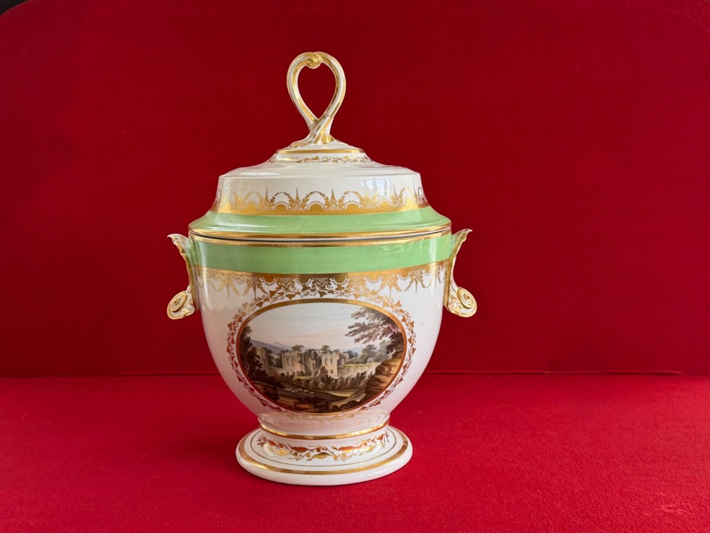 A late 18th-century Derby porcelain ice pail with twin scroll handles, a looping lid finial, an apple-green band, gold gilding, and a central oval landscape painting. View III
