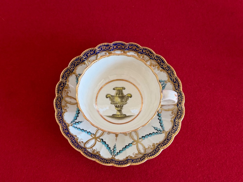 An 18th-century Worcester porcelain trio comprising a teacup, coffee cup, and saucer decorated with fluted moulding, blue swags, Classical urn motifs, and gold leaf gilding. View IV