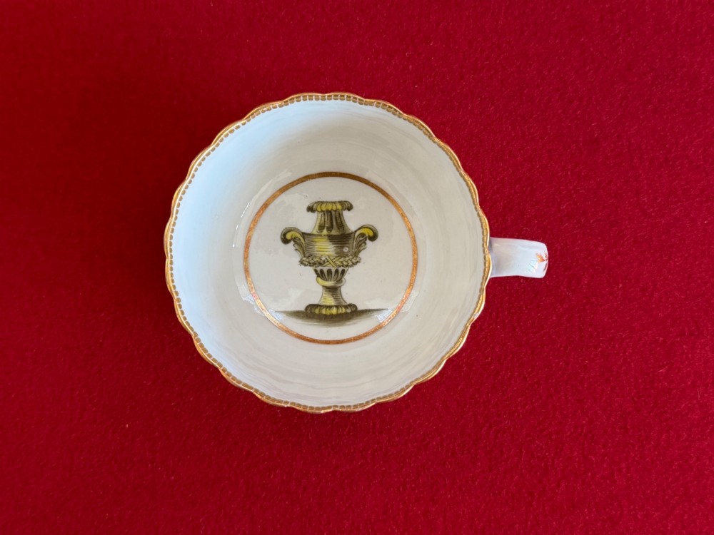 An 18th-century Worcester porcelain trio comprising a teacup, coffee cup, and saucer decorated with fluted moulding, blue swags, Classical urn motifs, and gold leaf gilding. View X