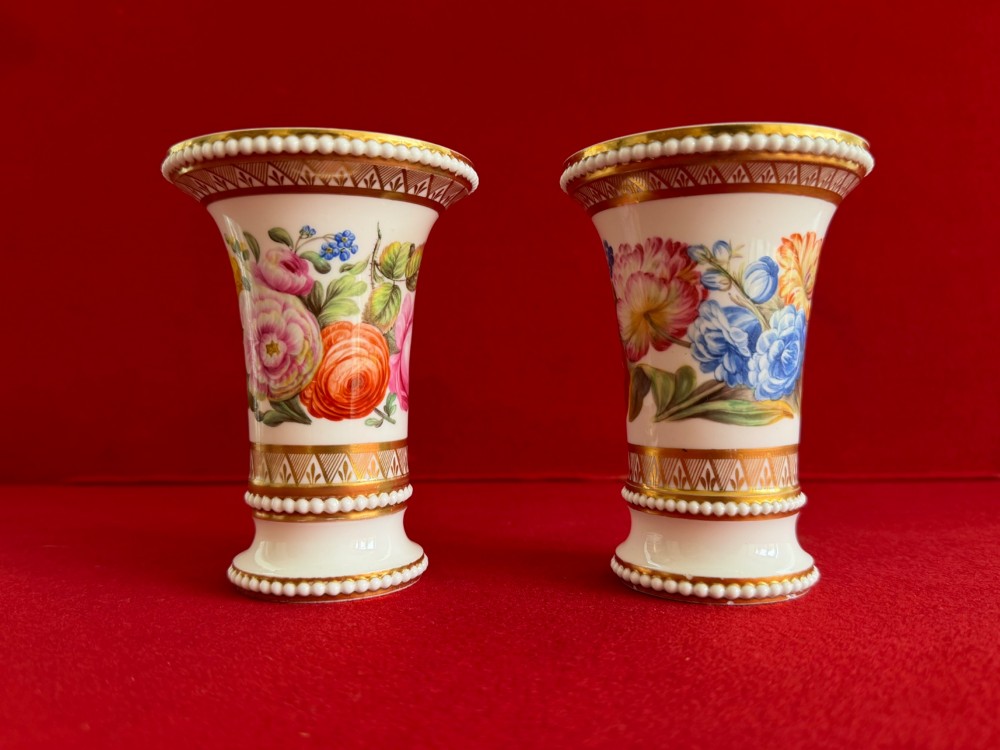 A pair of flared white antique porcelain spill vases painted with colourful floral bouquets and trimmed with gilded geometric borders and beaded rims. View IV
