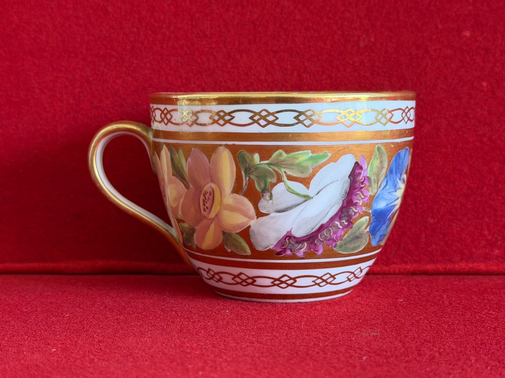 A Regency John Rose Coalport porcelain trio comprising a teacup, coffee can, and matching saucer featuring hand-painted pink roses on a gold ground. View VII