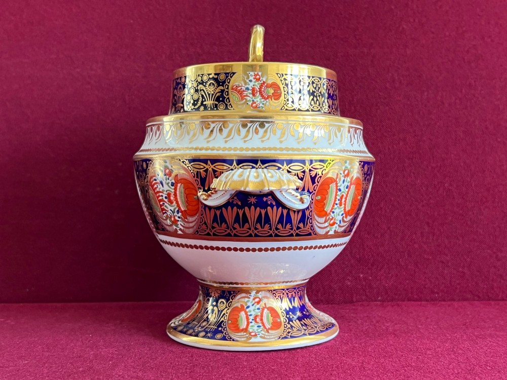 A Regency period porcelain sauce tureen with lid, decorated with cobalt blue and orange Imari patterns, gold gilding, and an armorial crest bearing the motto Forward. View IV