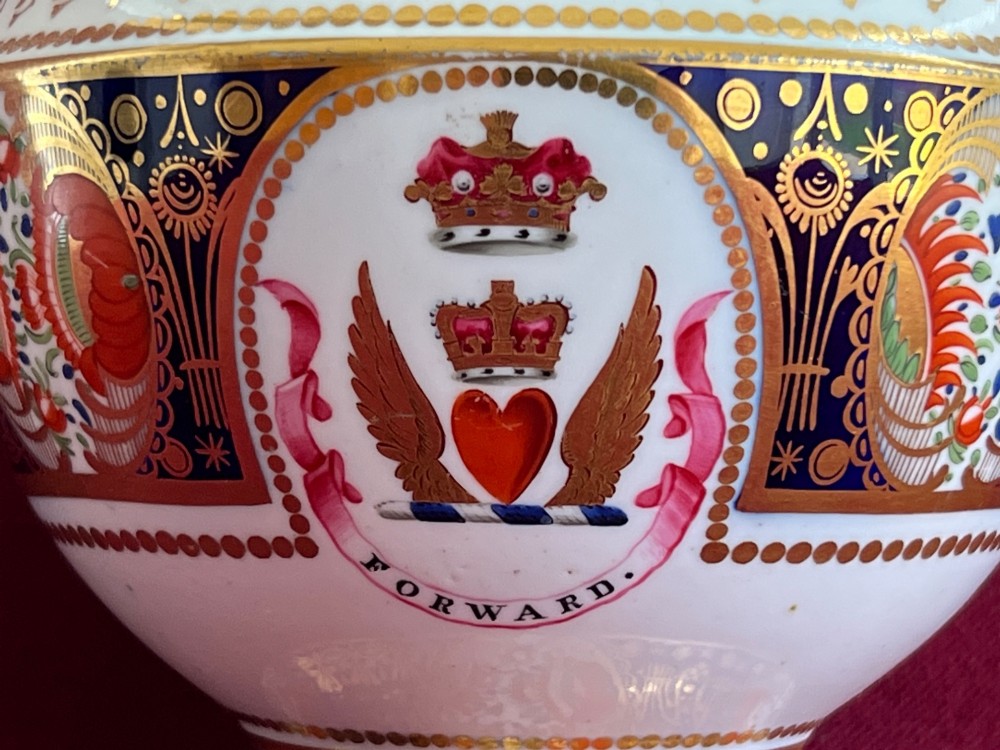 A Regency period porcelain sauce tureen with lid, decorated with cobalt blue and orange Imari patterns, gold gilding, and an armorial crest bearing the motto Forward. View V