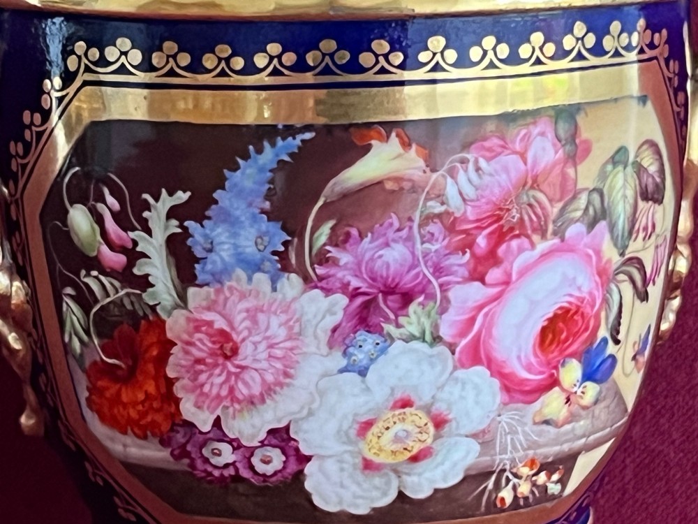A three-piece set of cobalt blue and gilded Minton porcelain urn vases featuring hand-painted floral panels on square plinths. View X
