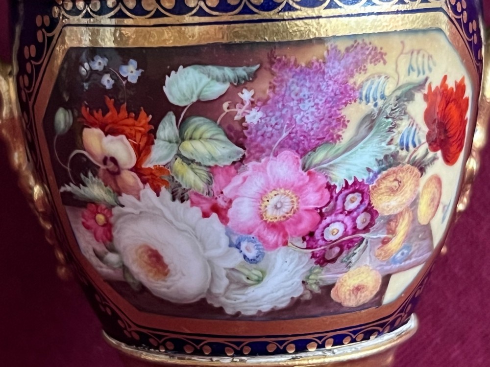 A three-piece set of cobalt blue and gilded Minton porcelain urn vases featuring hand-painted floral panels on square plinths. View XII