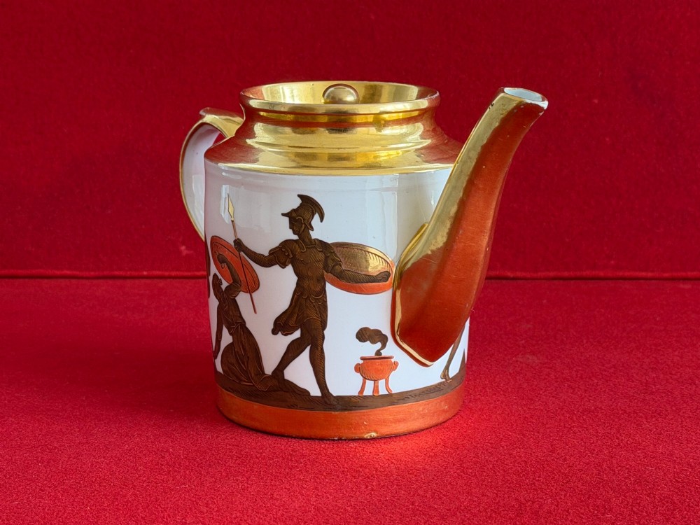 A Regency cylindrical porcelain teapot featuring a gilded spout and collar alongside hand-painted classical figures on a white ground. View V