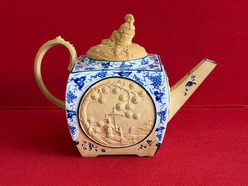 An eighteenth-century box-shaped Spode caneware teapot with moulded Chinoiserie relief panels, blue foliage borders, and a reclining figural lid finial. View III