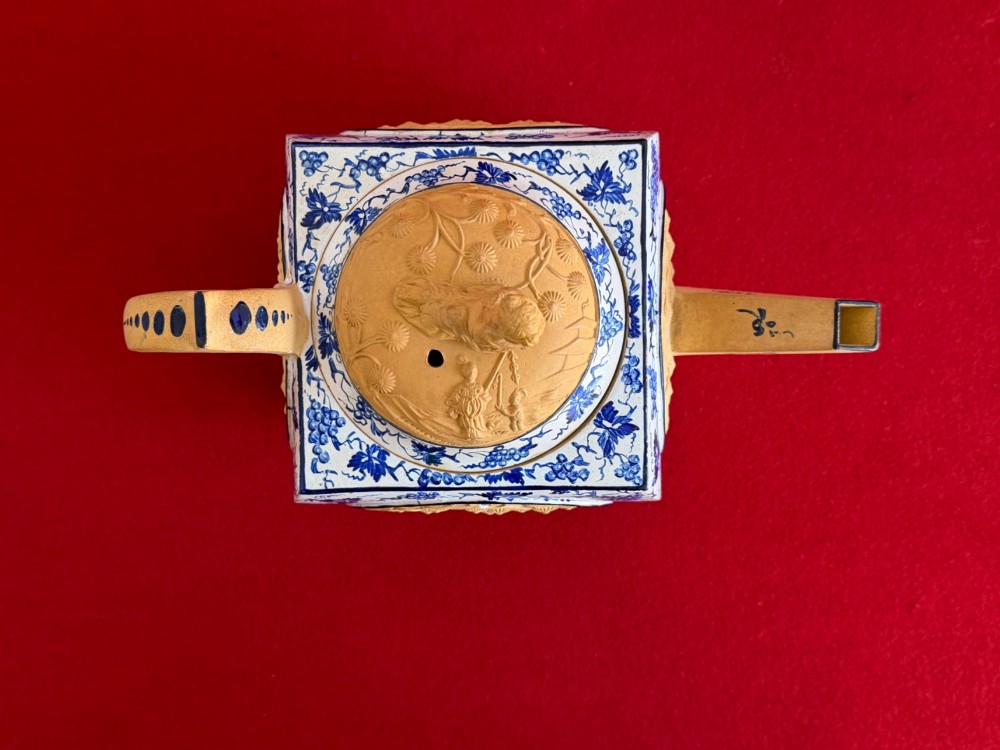 An eighteenth-century box-shaped Spode caneware teapot with moulded Chinoiserie relief panels, blue foliage borders, and a reclining figural lid finial. View VIII