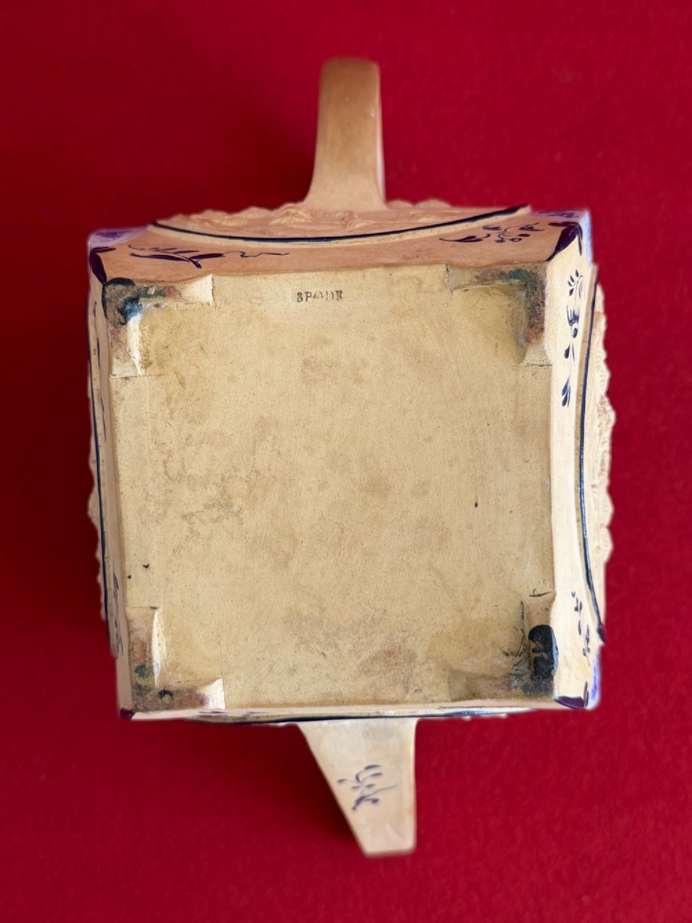 An eighteenth-century box-shaped Spode caneware teapot with moulded Chinoiserie relief panels, blue foliage borders, and a reclining figural lid finial. View IX