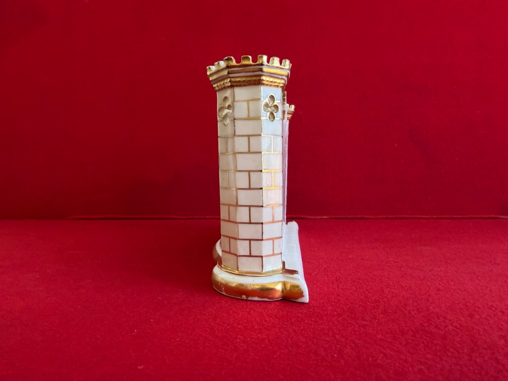 An English porcelain spill vase in the form of a castle with gilded turrets, crenellated rims, and a central painted landscape panel. View III