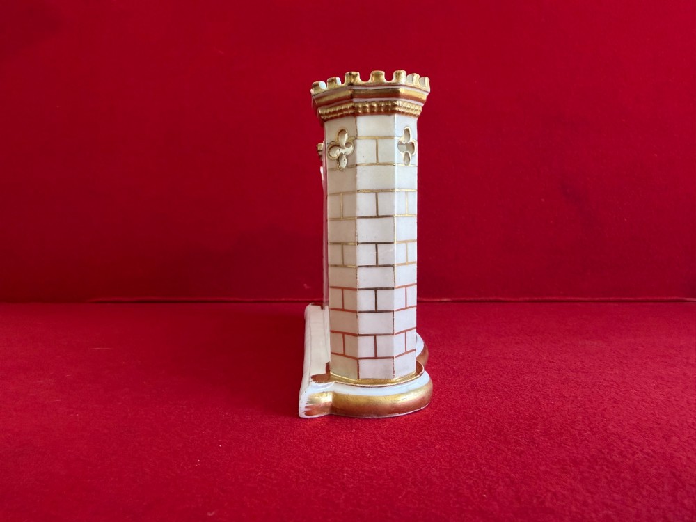 An English porcelain spill vase in the form of a castle with gilded turrets, crenellated rims, and a central painted landscape panel. View IV