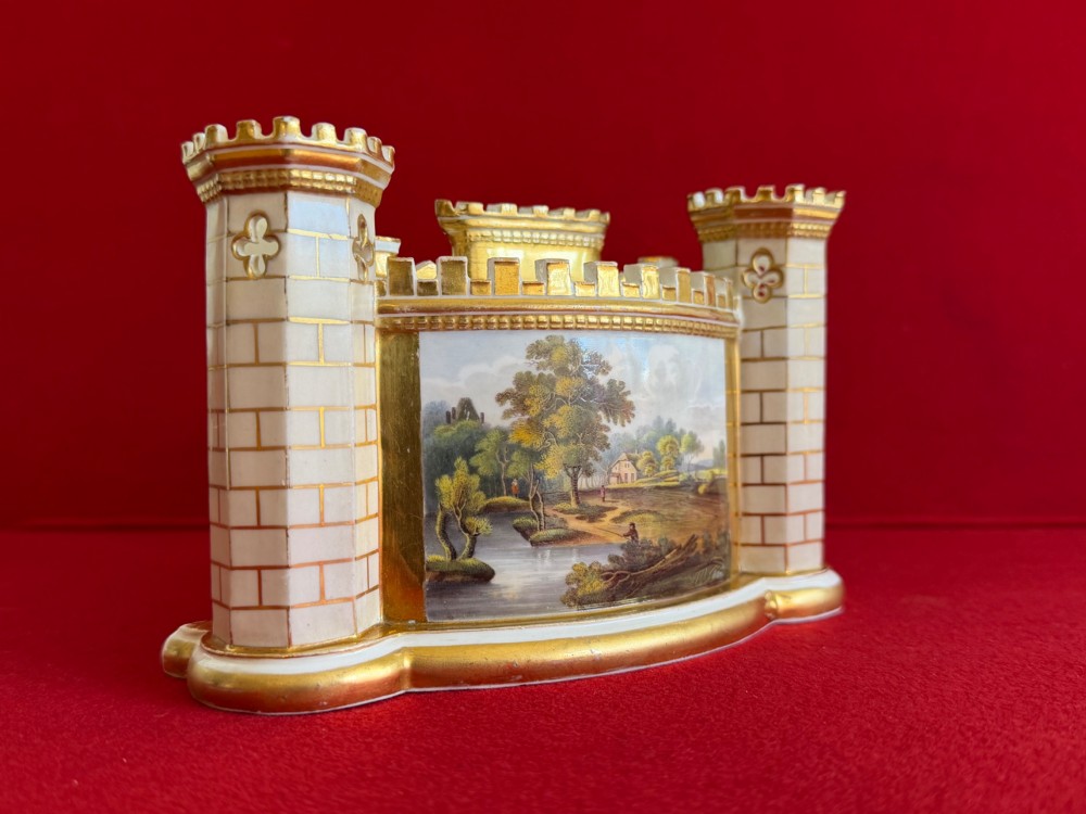 An English porcelain spill vase in the form of a castle with gilded turrets, crenellated rims, and a central painted landscape panel. View VI