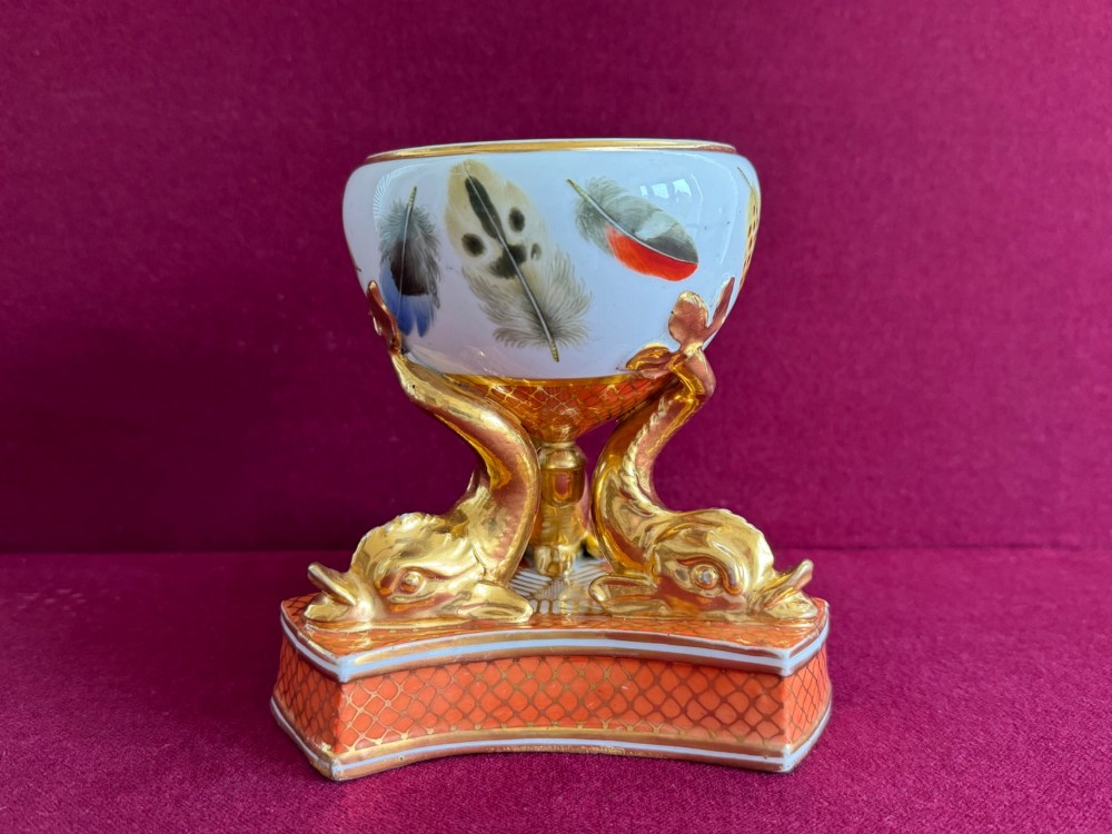 A nineteenth-century Chamberlain Worcester porcelain pastille burner with hand-painted feathers on a white bowl supported by gilt dolphins.