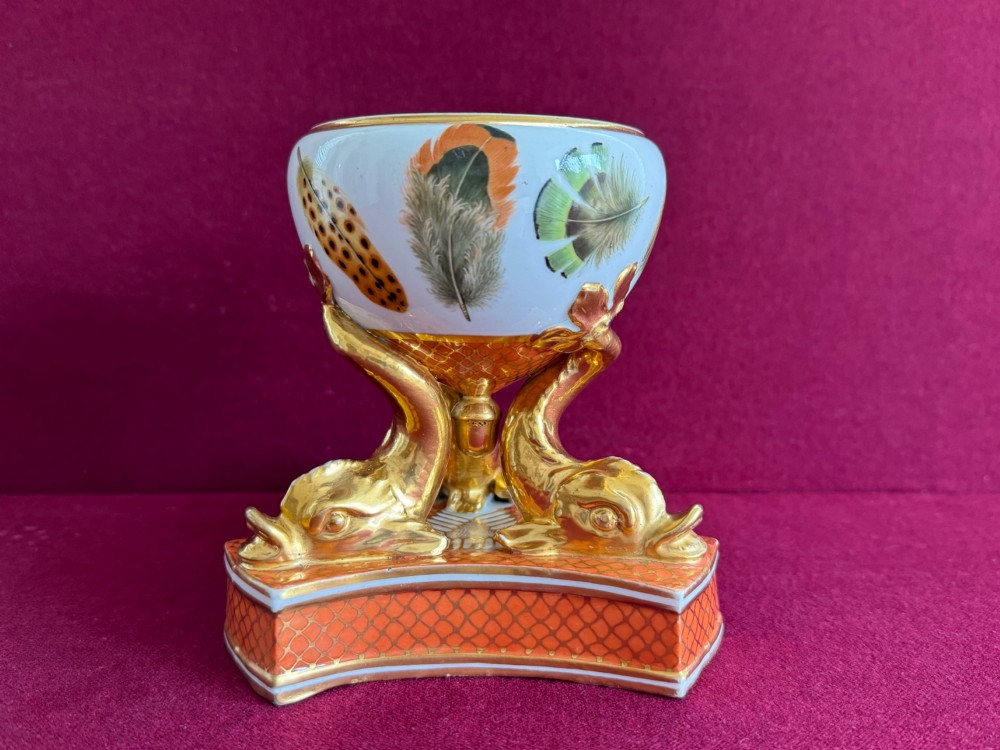 A nineteenth-century Chamberlain Worcester porcelain pastille burner with hand-painted feathers on a white bowl supported by gilt dolphins. View II