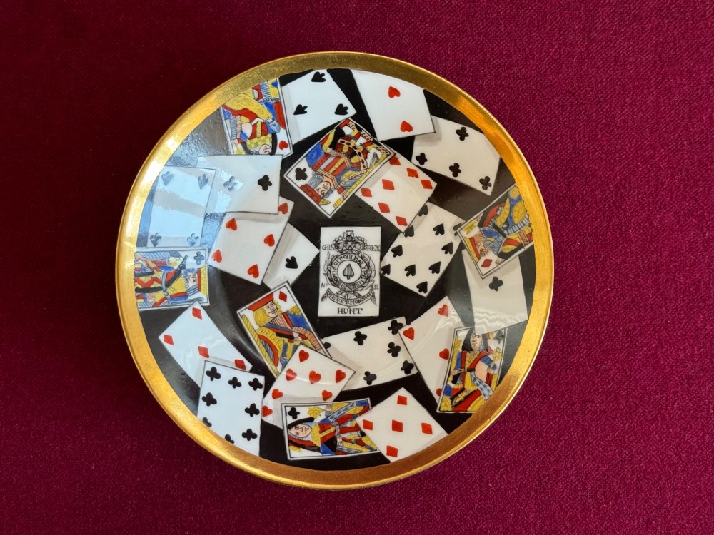 An antique porcelain teacup and saucer featuring a gilded exterior and a detailed hand-painted playing card pattern on the interior surfaces. View III