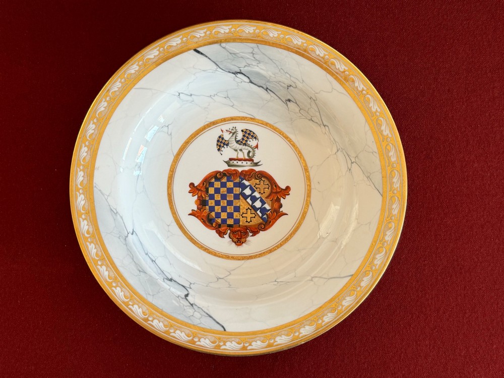 A circular Regency porcelain soup plate featuring a central heraldic crest, surrounded by a faux-marble ground and a broad gilded rim. View V