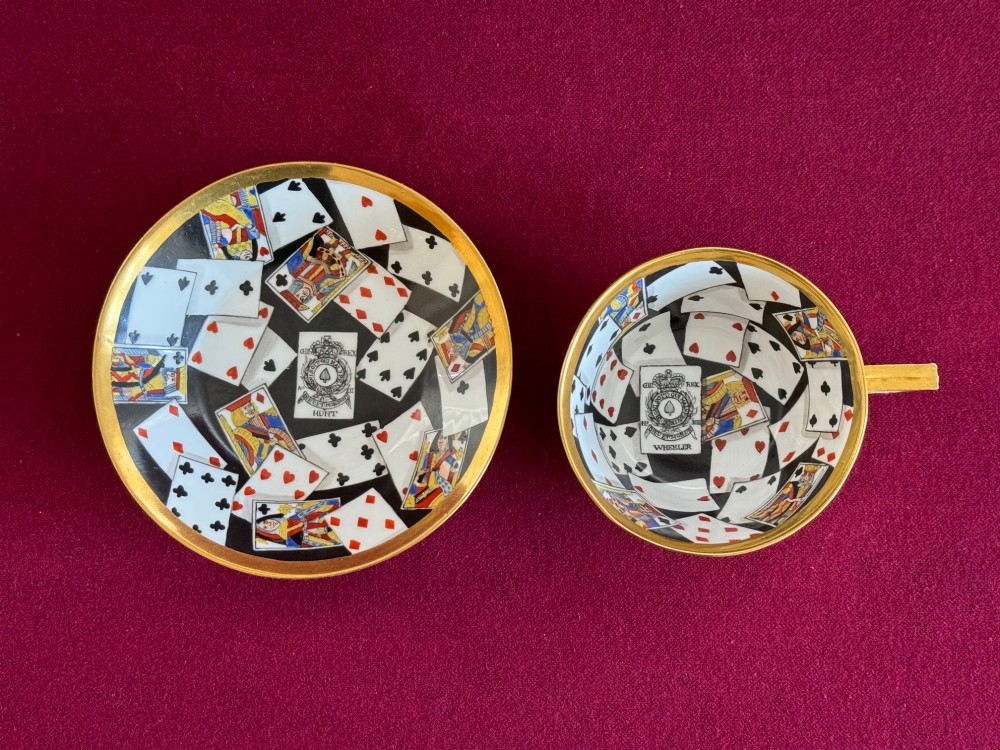 An early nineteenth-century porcelain teacup decorated with terracotta classical foliage alongside a saucer painted with a trompe loeil playing card pattern. View II
