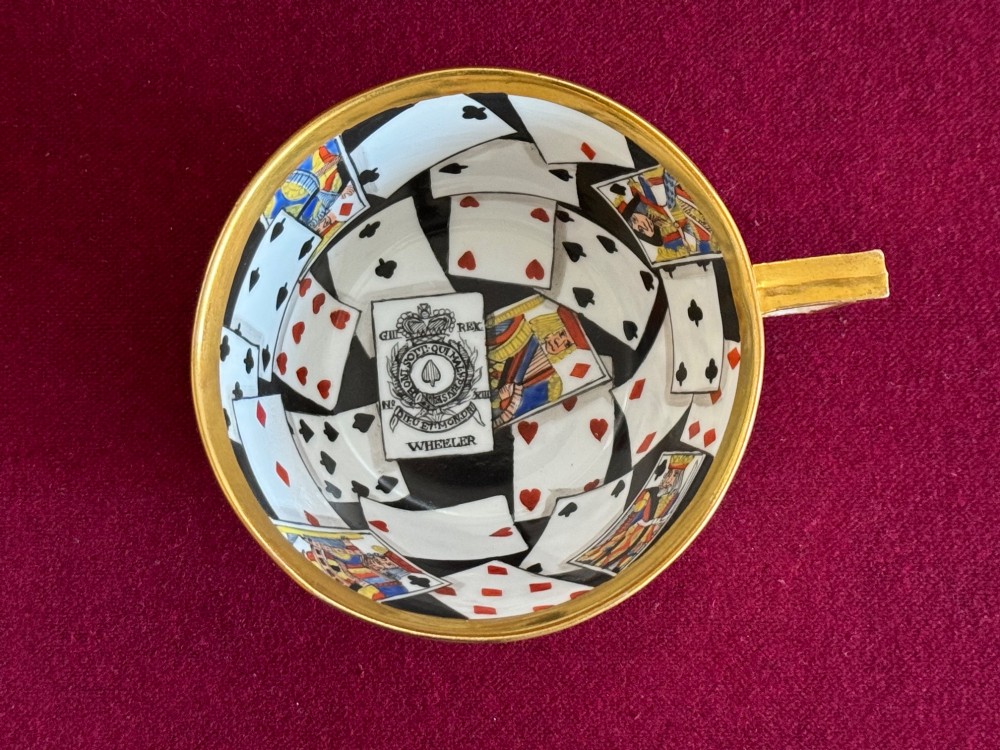 An early nineteenth-century porcelain teacup decorated with terracotta classical foliage alongside a saucer painted with a trompe loeil playing card pattern. View IV