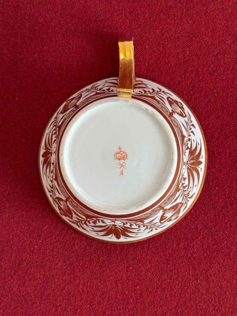 An early nineteenth-century porcelain teacup decorated with terracotta classical foliage alongside a saucer painted with a trompe loeil playing card pattern. View VII