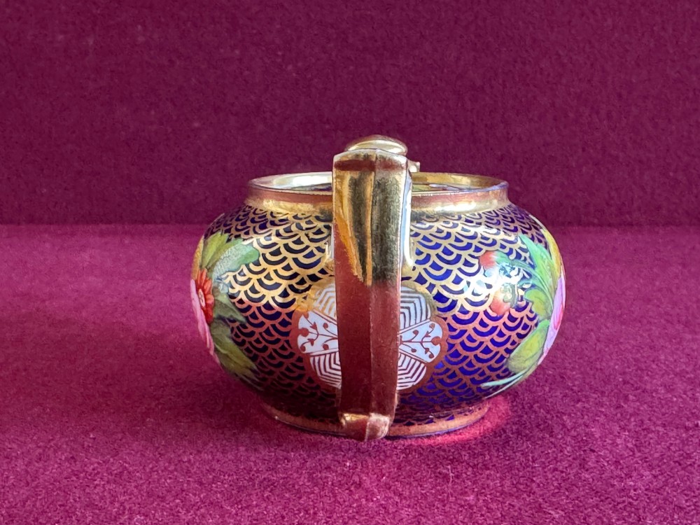 An antique Regency period miniature porcelain teapot decorated with intricate gold scale patterns on dark blue porcelain and hand-painted floral panels. View VI
