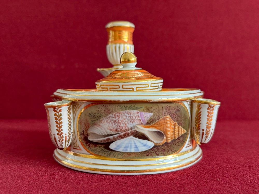 A Regency Flight & Barr Worcester porcelain inkstand painted with realistic seashell panels, gilded borders, quill holders, and a central candlestick.