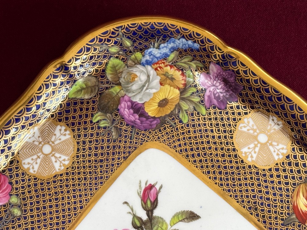 A square Regency porcelain tray featuring hand-painted floral bouquets, an intricate gilt scale pattern over a cobalt blue ground, and a central white reserve with pink roses. View II