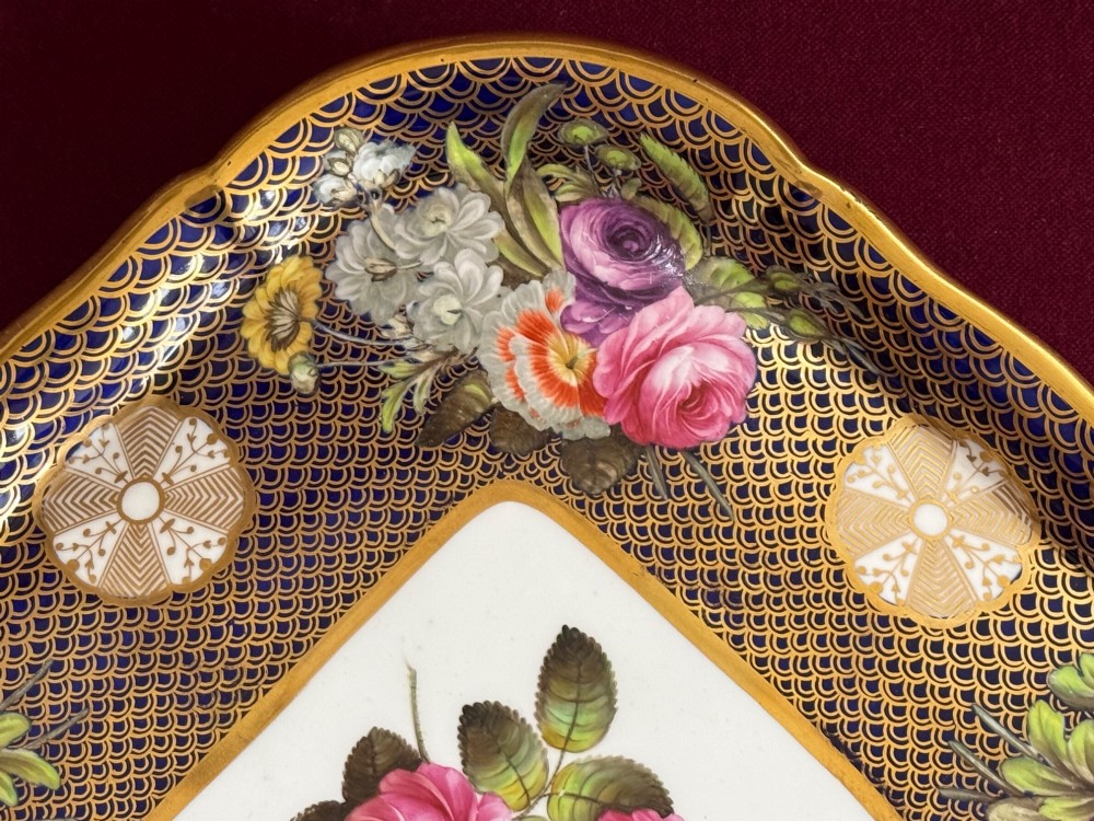 A square Regency porcelain tray featuring hand-painted floral bouquets, an intricate gilt scale pattern over a cobalt blue ground, and a central white reserve with pink roses. View IV