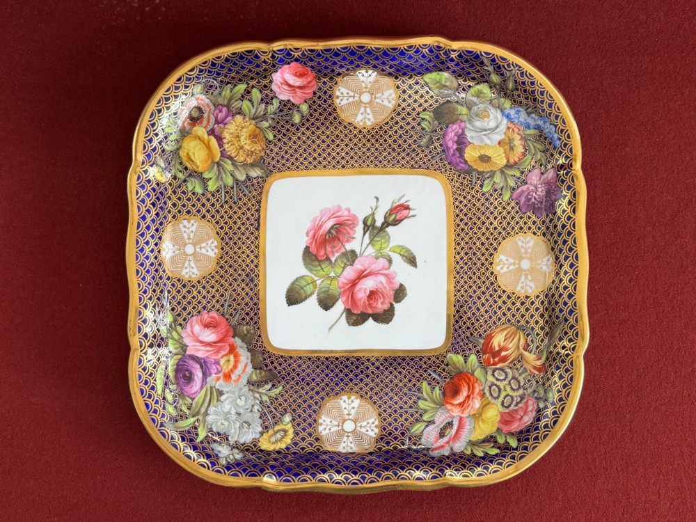 A square Regency porcelain tray featuring hand-painted floral bouquets, an intricate gilt scale pattern over a cobalt blue ground, and a central white reserve with pink roses. View VIII