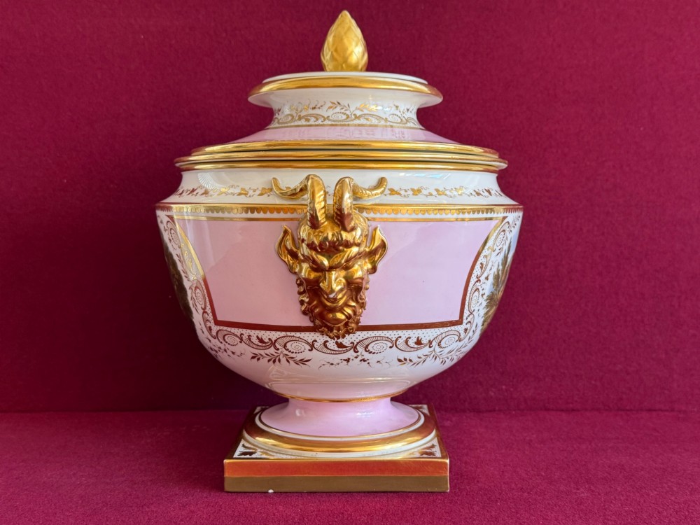 A pair of antique Regency porcelain ice pails featuring pink and white grounds, hand-painted landscape scenes, gilded lion mask handles, and pinecone finials. View VII