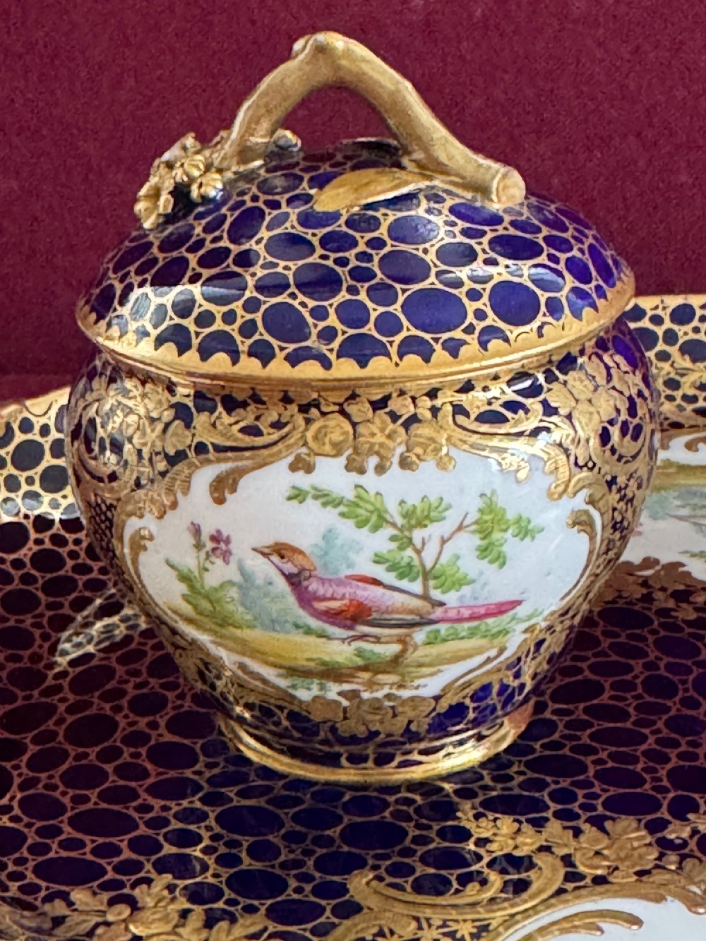 An oval cobalt blue porcelain inkstand decorated with gold honeycomb diapering, hand-painted bird cartouches, and two covered inkwells with gilt branch handles. View IV