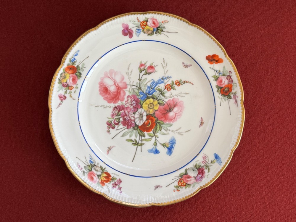 A pair of circular white Regency porcelain plates with lobed gilded rims and hand-painted floral bouquets at the centre and border. View III