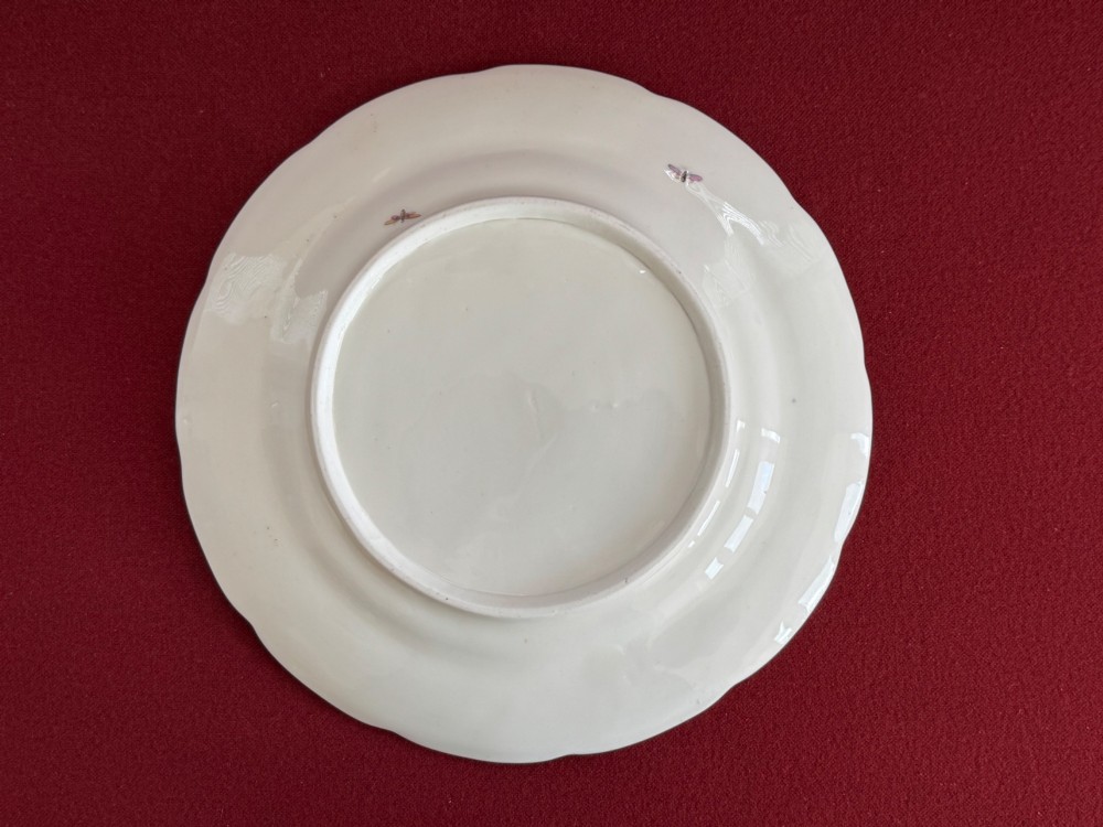 A pair of circular white Regency porcelain plates with lobed gilded rims and hand-painted floral bouquets at the centre and border. View IV