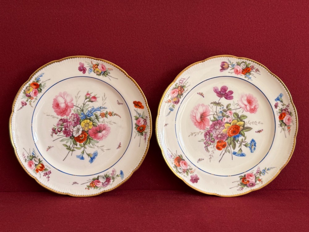 A pair of circular white Regency porcelain plates with lobed gilded rims and hand-painted floral bouquets at the centre and border. View VI