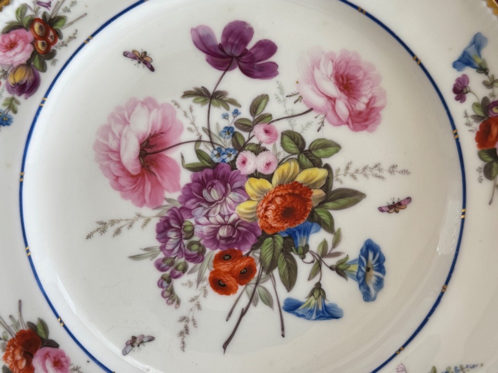 A pair of circular white Regency porcelain plates with lobed gilded rims and hand-painted floral bouquets at the centre and border. View VII