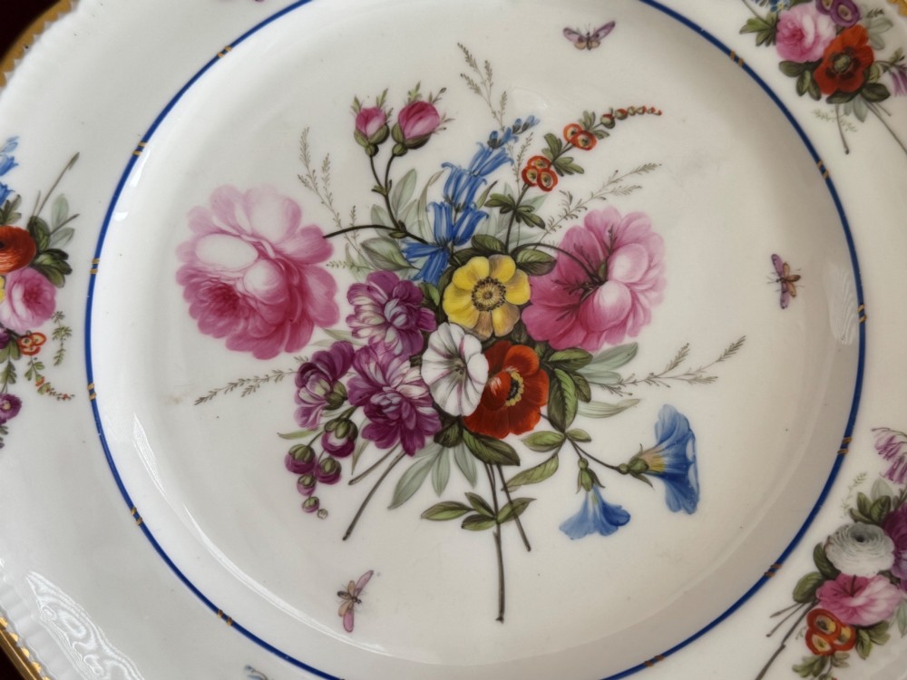 A pair of circular white Regency porcelain plates with lobed gilded rims and hand-painted floral bouquets at the centre and border. View VIII