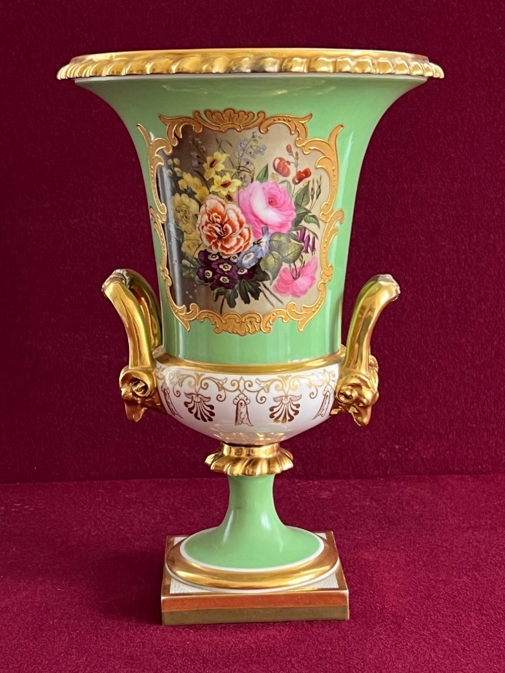 A Flight, Barr & Barr Worcester porcelain Campana shape vase featuring an apple green ground, floral enamel painting, gilt twin handles, and a square base.