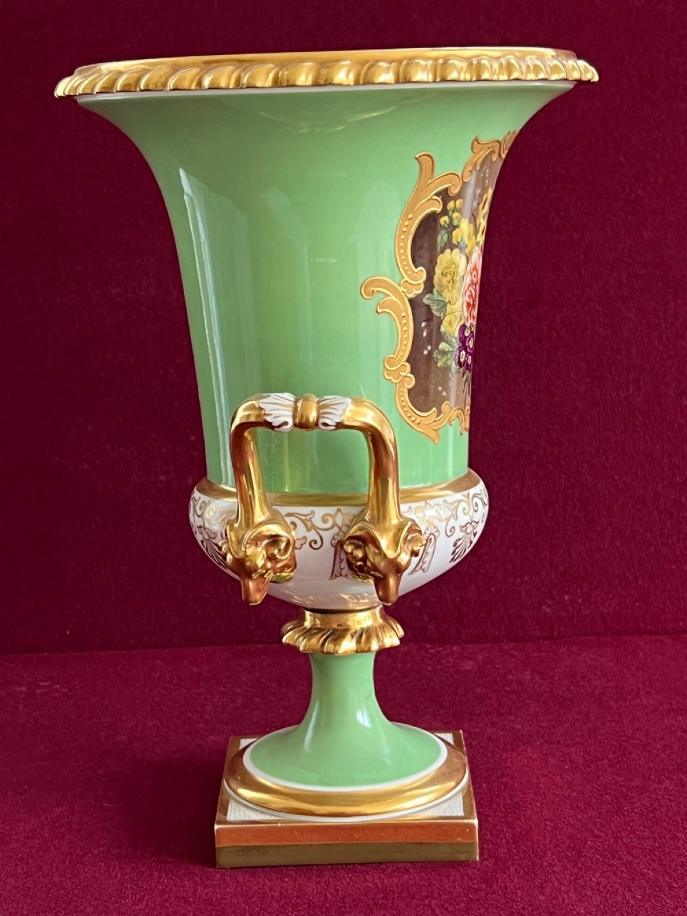 A Flight, Barr & Barr Worcester porcelain Campana shape vase featuring an apple green ground, floral enamel painting, gilt twin handles, and a square base. View II