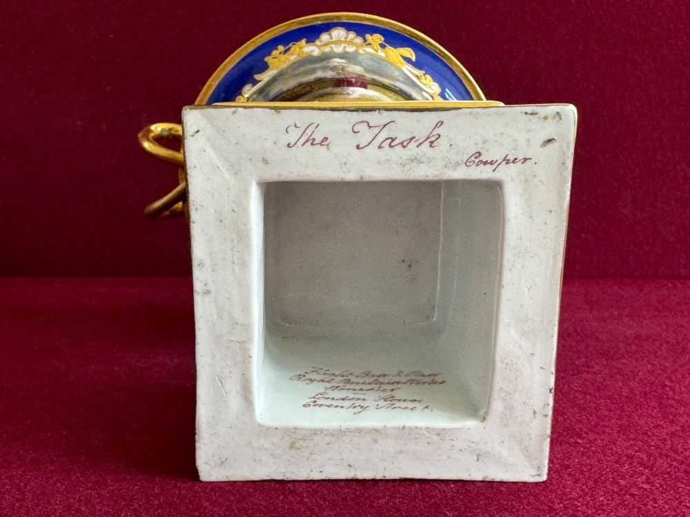 A Regency cobalt blue and gilded porcelain urn featuring a central hand-painted panel of a standing figure in a landscape, twin scroll handles, beaded borders, and a square pedestal base. View IX
