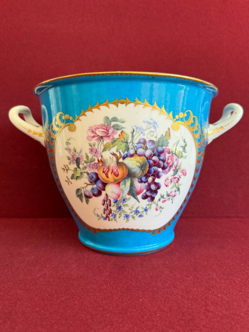 A pair of turquoise porcelain bottle coolers featuring hand-painted fruit cartouches framed by gilded scrollwork and twin handles. View VII