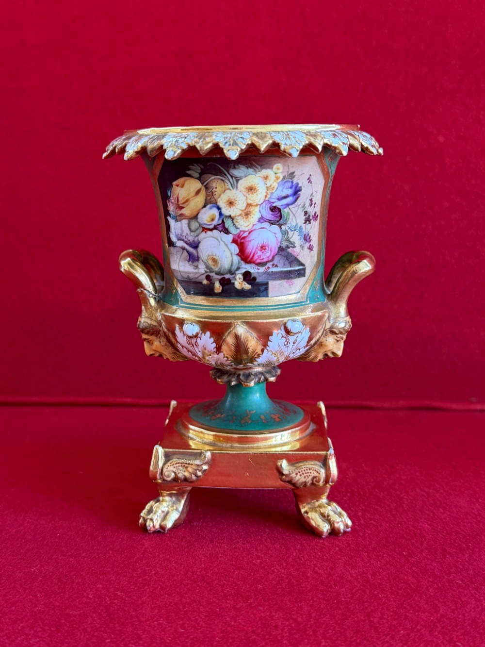 A three-piece antique porcelain garniture set featuring green and gold gilded urns with hand-painted floral panels on pedestal bases with paw feet. View IV