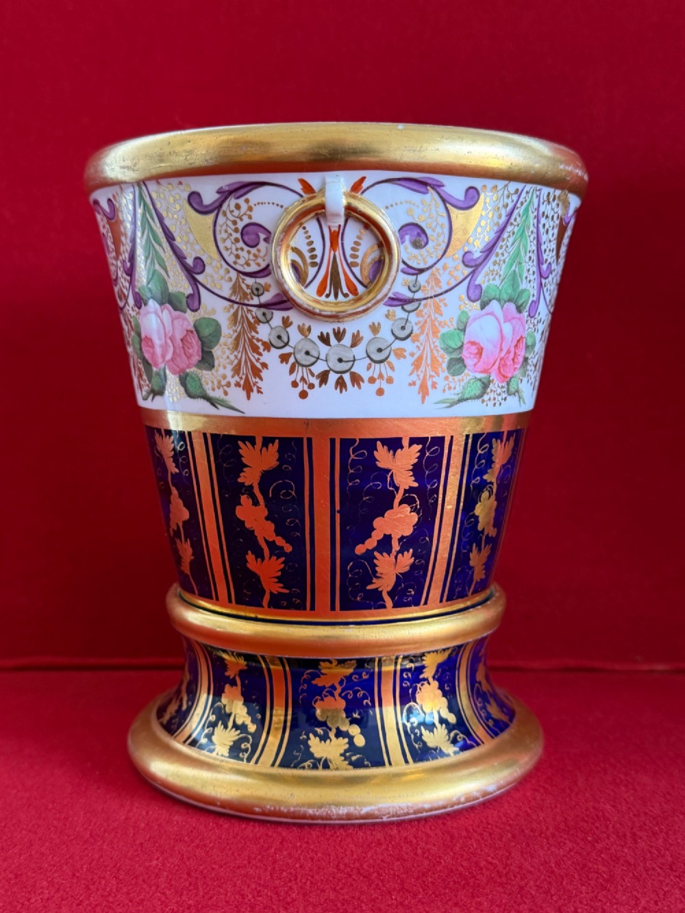 A three-piece English Regency Spode porcelain garniture featuring a central twin-handled urn flanked by two beaker-shaped vases decorated with cobalt blue panels, hand-painted pink floral motifs, and detailed gilt scrollwork. View IV