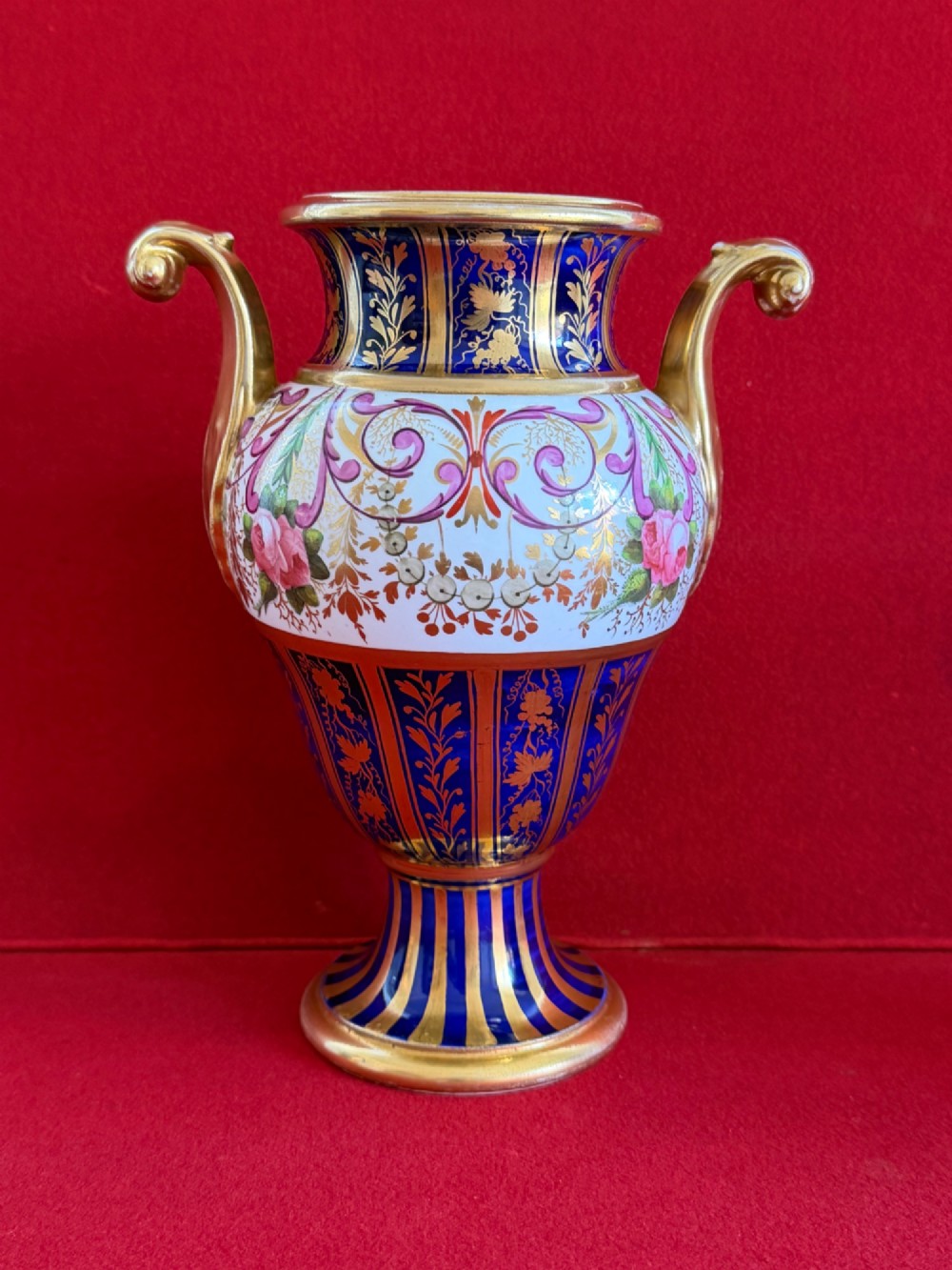 A three-piece English Regency Spode porcelain garniture featuring a central twin-handled urn flanked by two beaker-shaped vases decorated with cobalt blue panels, hand-painted pink floral motifs, and detailed gilt scrollwork. View VIII