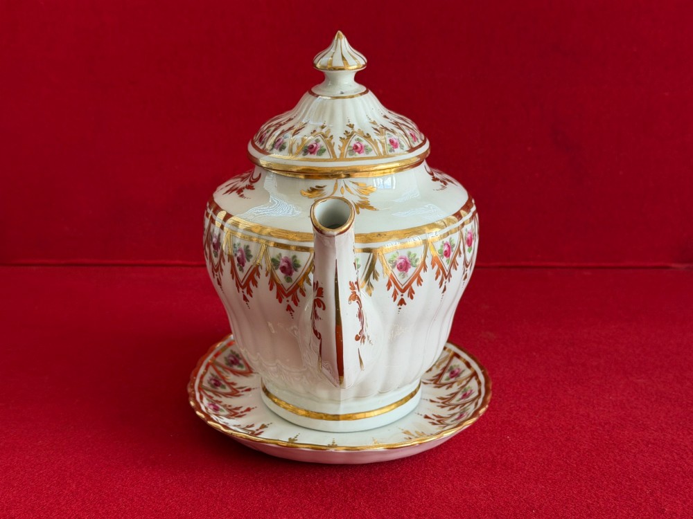 An 18th-century fluted white porcelain teapot and matching oval stand decorated with hand-painted pink floral motifs and gilded geometric borders. View II