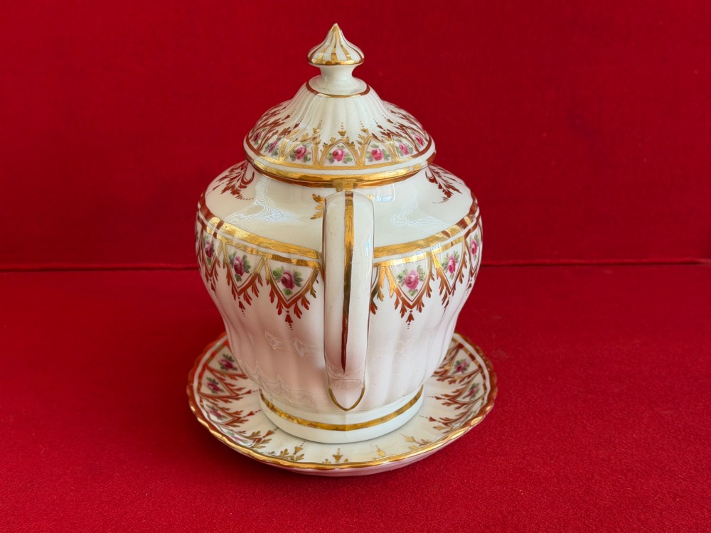 An 18th-century fluted white porcelain teapot and matching oval stand decorated with hand-painted pink floral motifs and gilded geometric borders. View IV