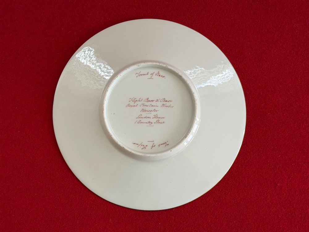 An antique Flight, Barr and Barr Worcester porcelain covered chocolate cup with two handles and matching saucer, decorated with hand-painted landscape and floral panels amid gold vermicelli detailing. View VI